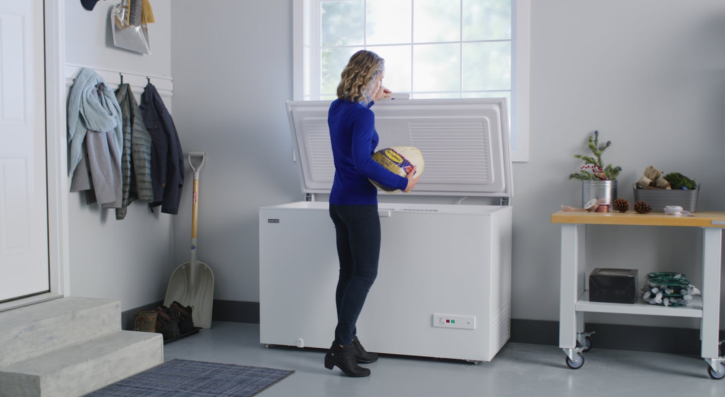 Woman removing a frozen turkey from a Maytag® chest freezer Woman removing a frozen turkey from a Maytag® chest freezer