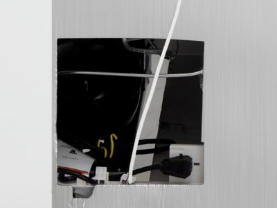 Wall cutout with power outlets and cords behind drywall