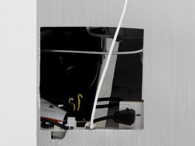 Wall cutout with power outlets and cords behind drywall