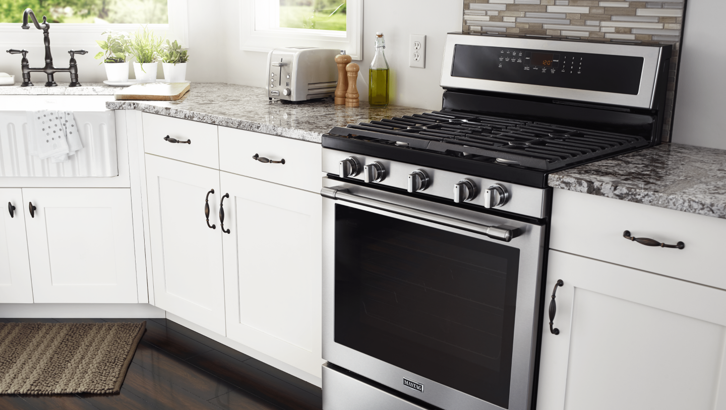 Maytag® gas range installed between white kitchen cabinets Maytag® gas range installed between white kitchen cabinets
