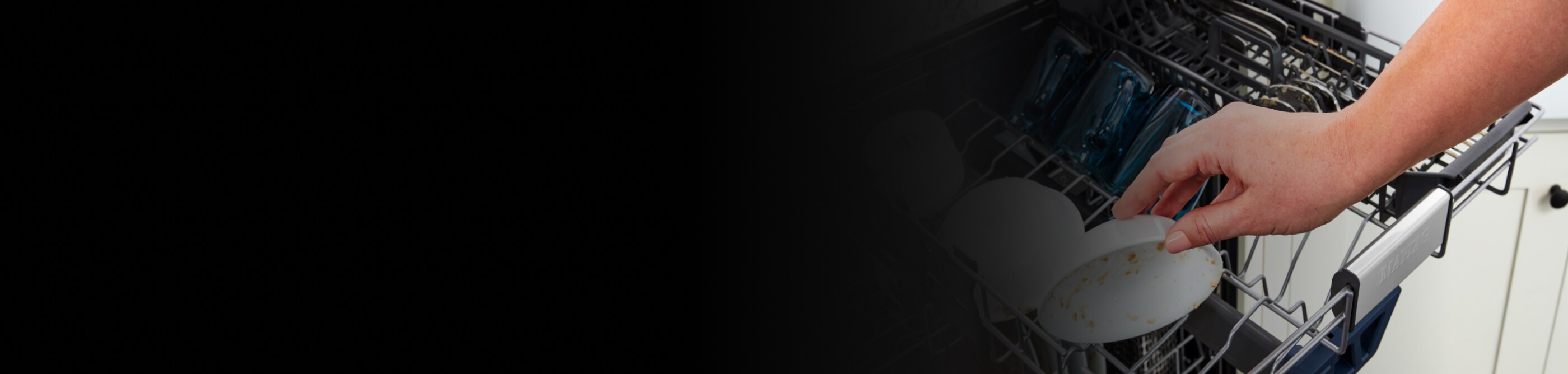 Hand placing dirty bowl in the top rack of a dishwasher