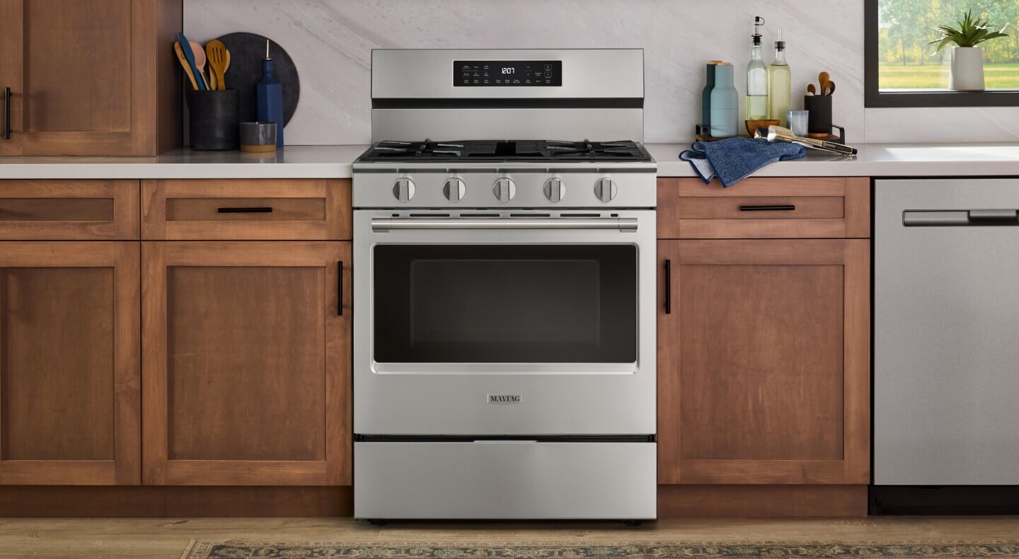 Stainless steel Maytag® gas range in modern brown cabinetry