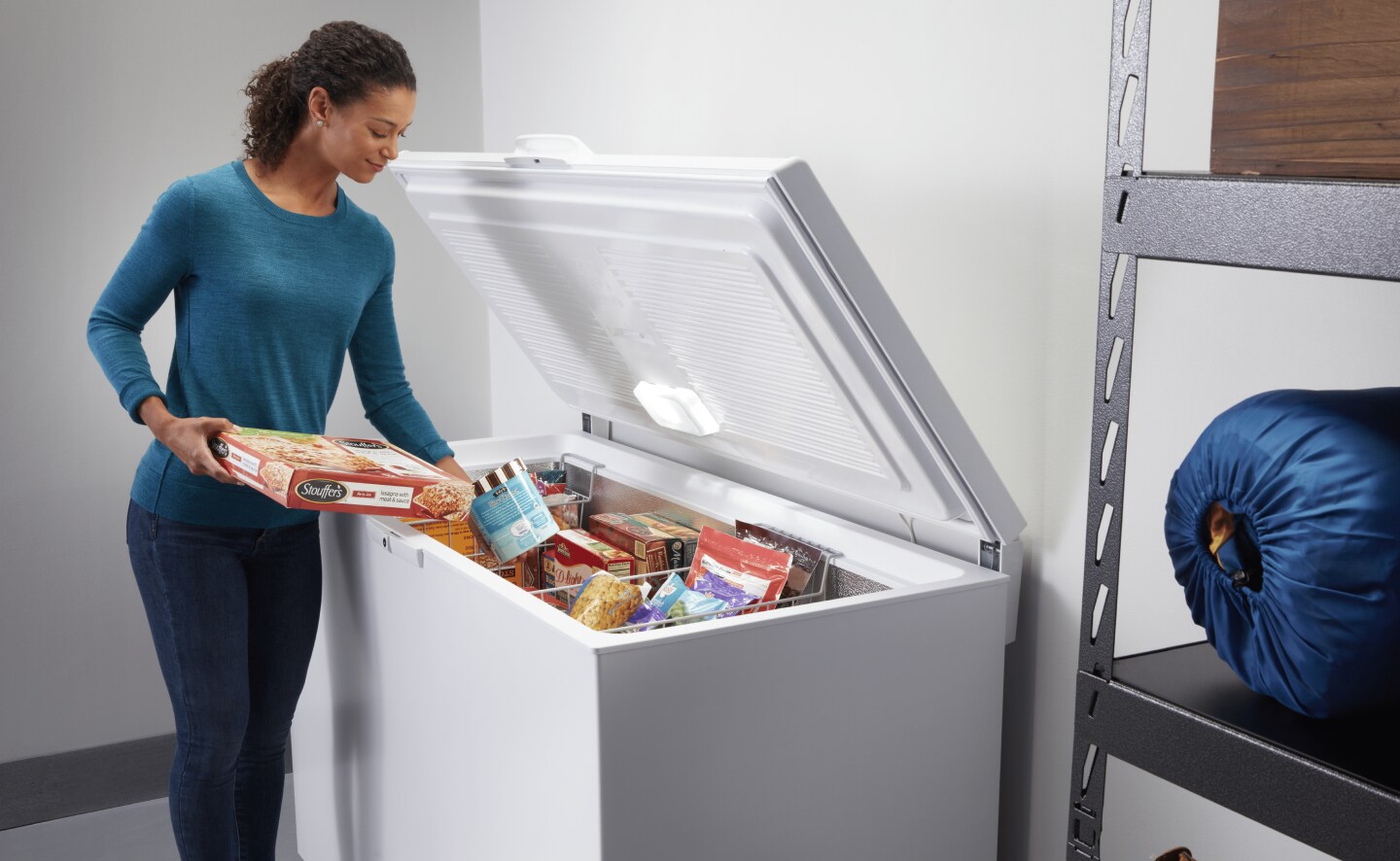 Person loading frozen food into chest freezer baskets Person loading frozen food into chest freezer baskets