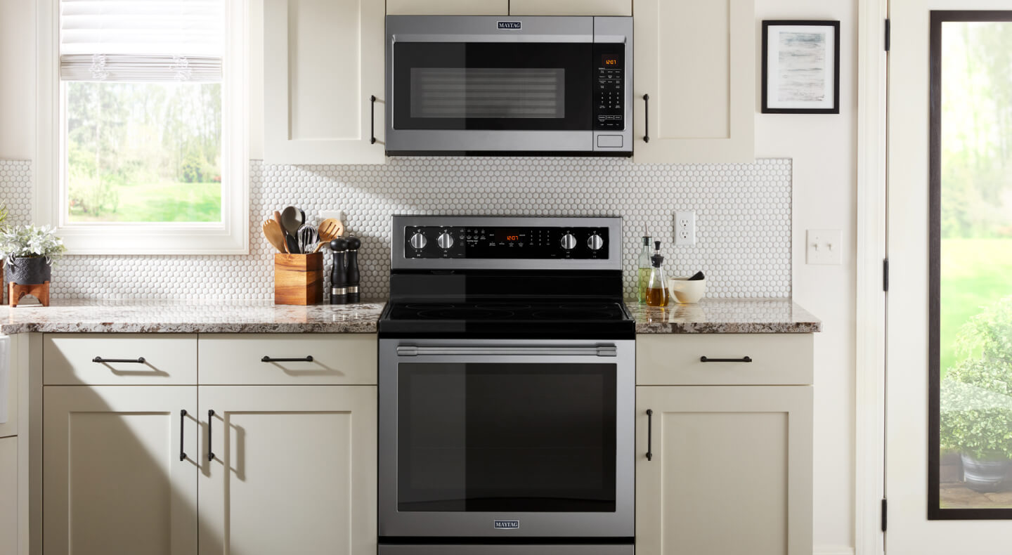 A bright kitchen with a stainless steel range and microwave