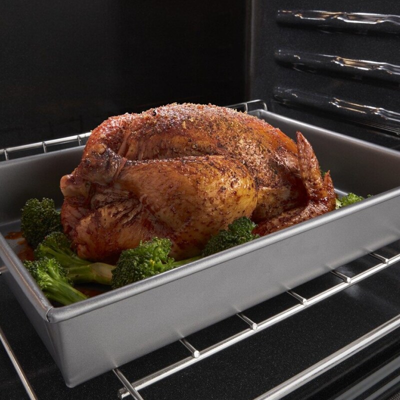 Cooked turkey in a roasting pan with vegetables