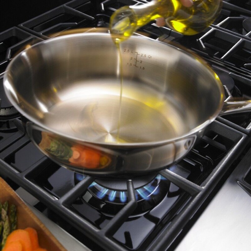 Oil being poured into a saucepan on an active stovetop