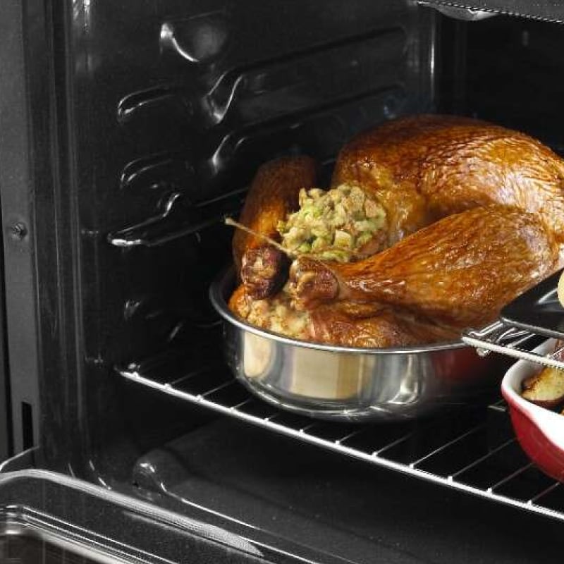 A stuffed, cooked turkey in the oven with other dishes