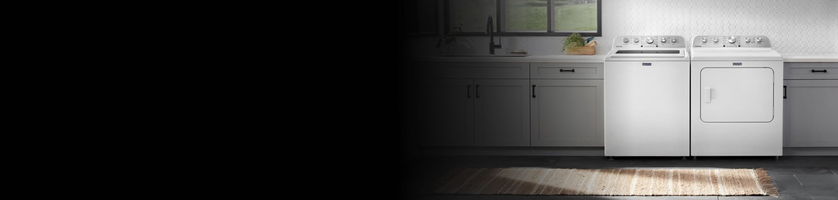 White front load laundry pair in between grey cabinets in a laundry room