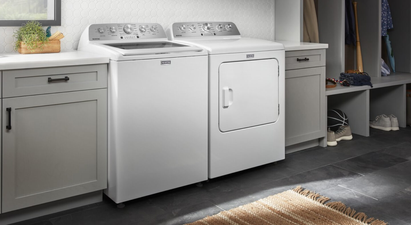 White Maytag® top load laundry pair between gray cabinetry