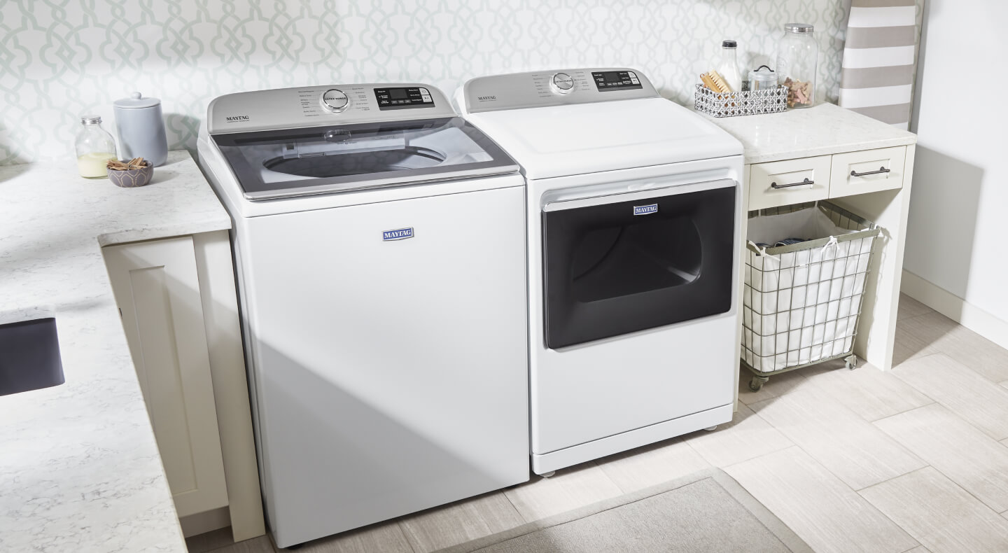 An all-white laundry room in a home with a top load washer and front load dryer