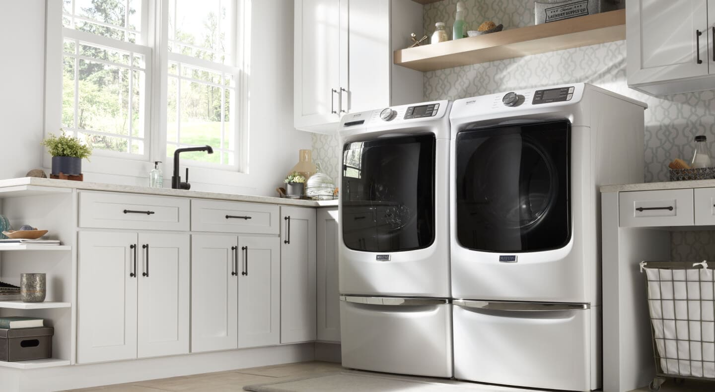 An all-white laundry room in a home with a washer and dryer side by side