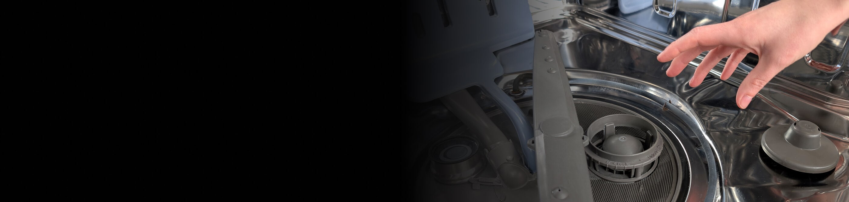 A hand reaching toward a dishwasher filter