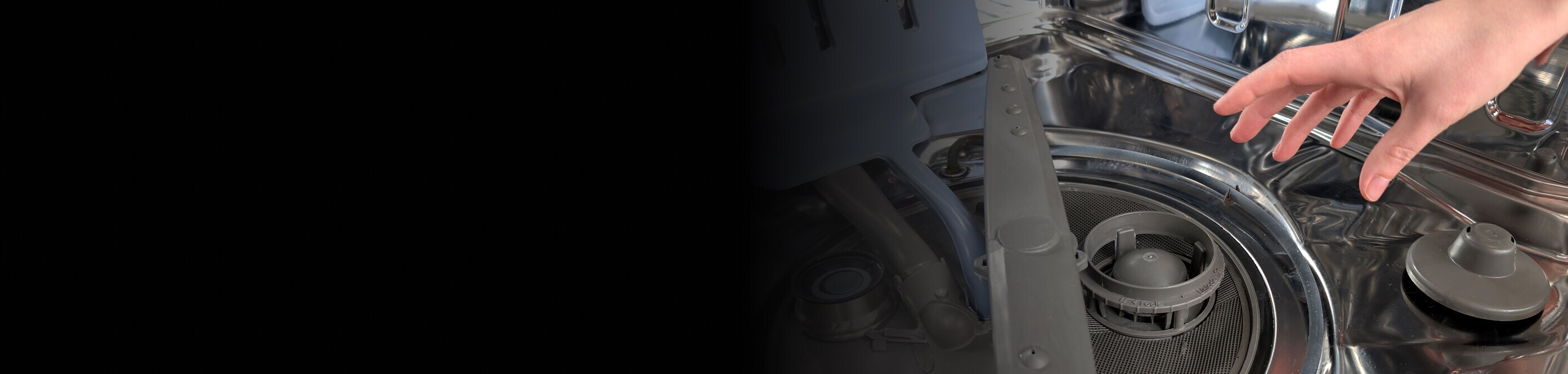 A hand reaching toward a dishwasher filter