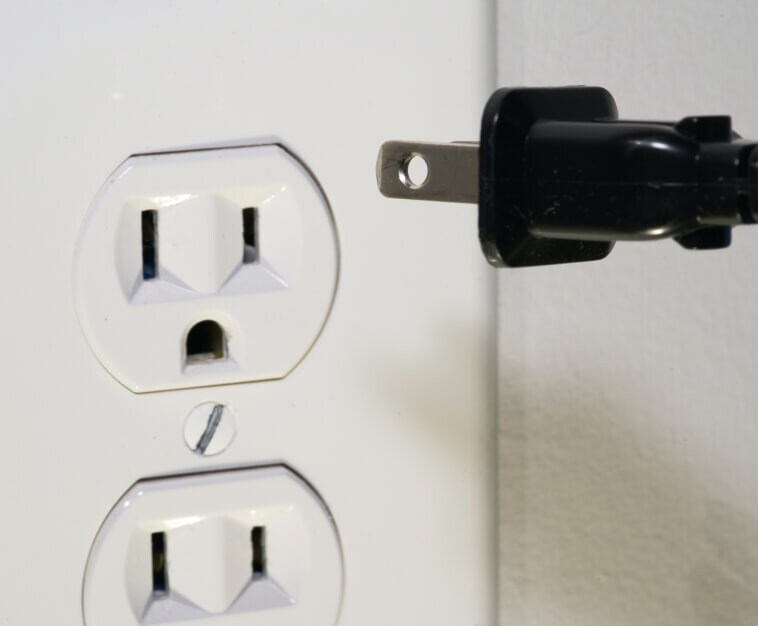 Power cord being unplugged from electrical outlet 