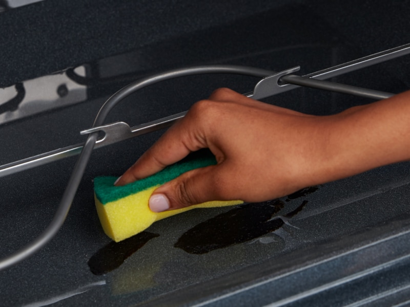 Person using a sponge to clean inside of oven Person using a sponge to clean inside of oven