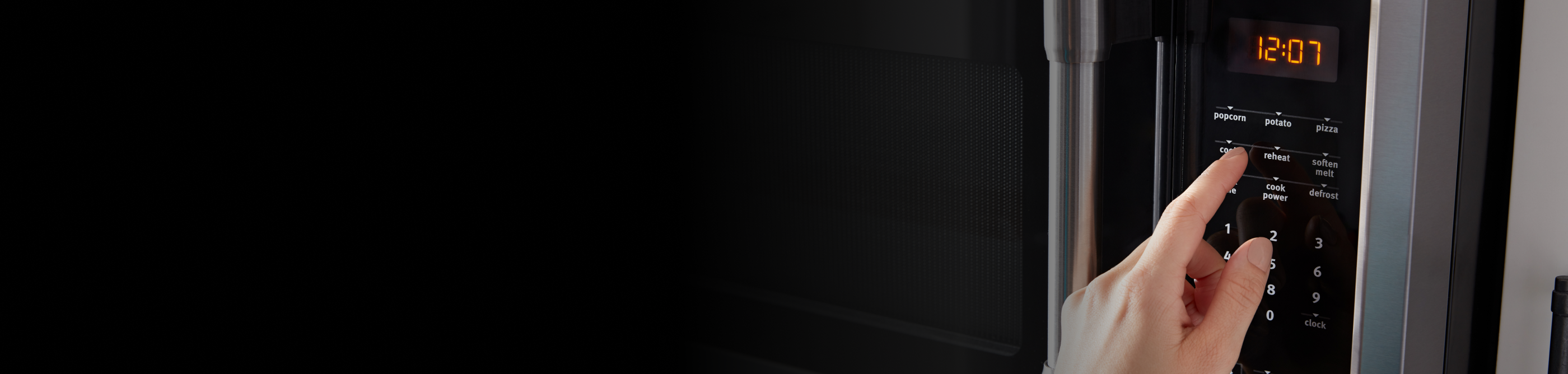 Person selecting settings on a stainless steel, over-the-range microwave control panel