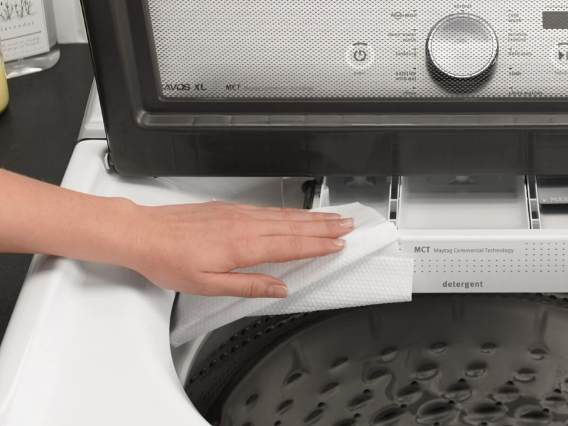 Person wiping detergent dispenser