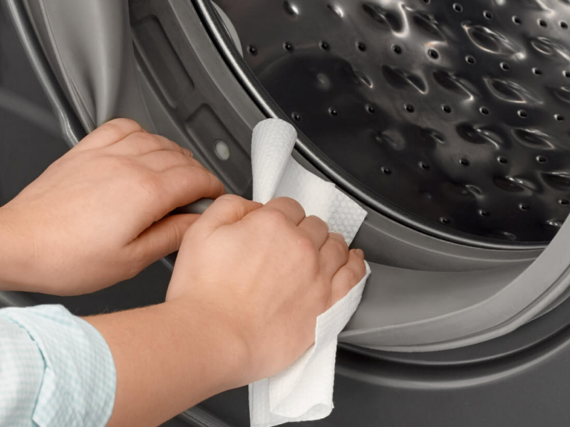 Person wiping inside of washing machine door