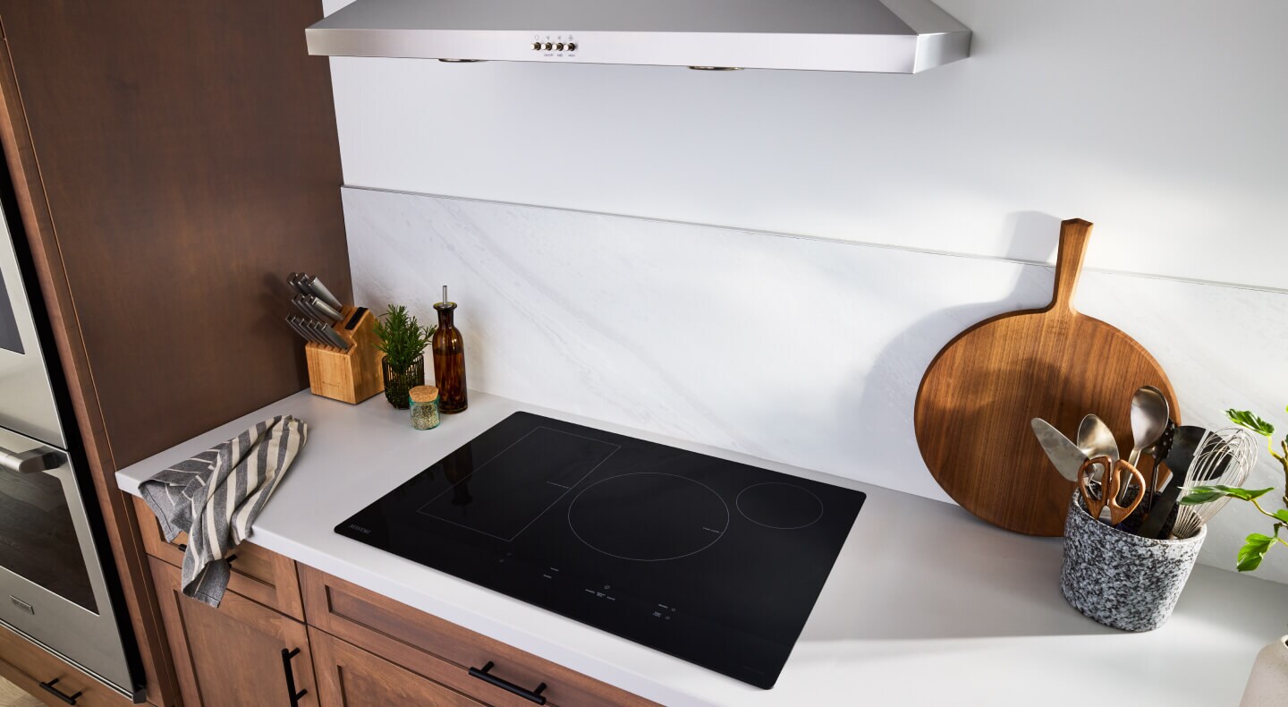 An induction cooktop surrounded by white countertops and brown cabinetry