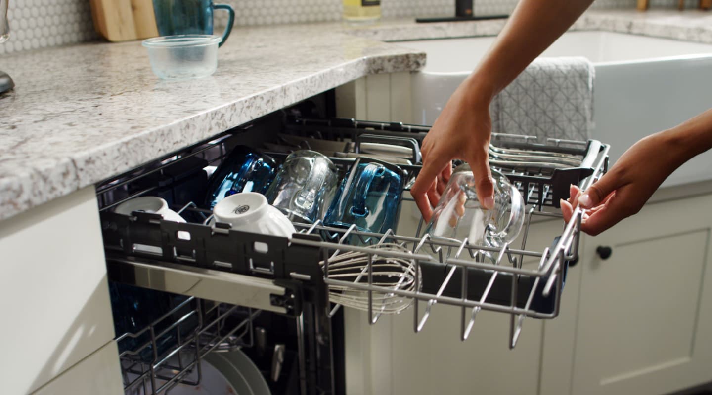 Person placing glasses on third-level rack of dishwasher Person placing glasses on third-level rack of dishwasher