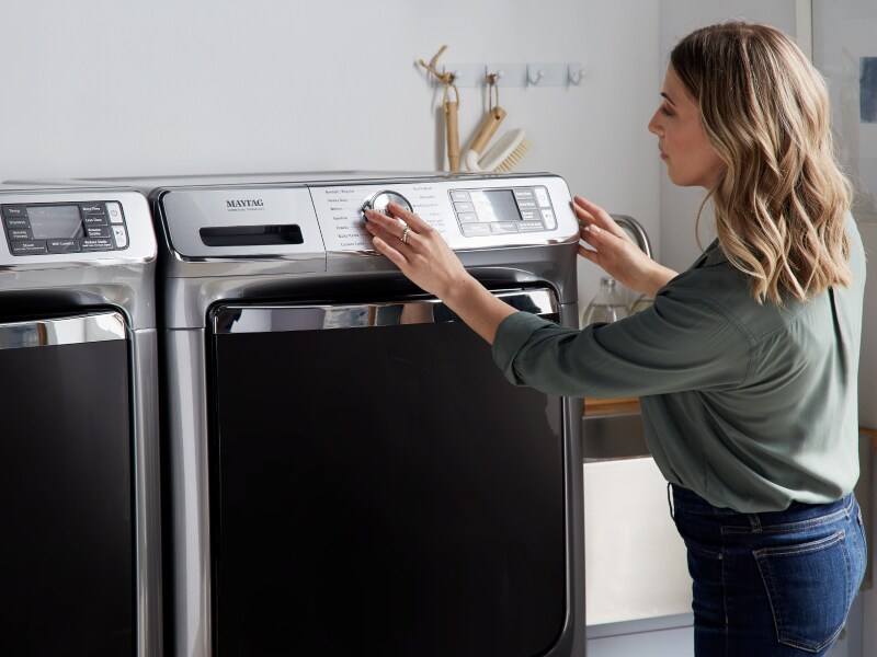 Person selecting a cycle on a Maytag® dryer