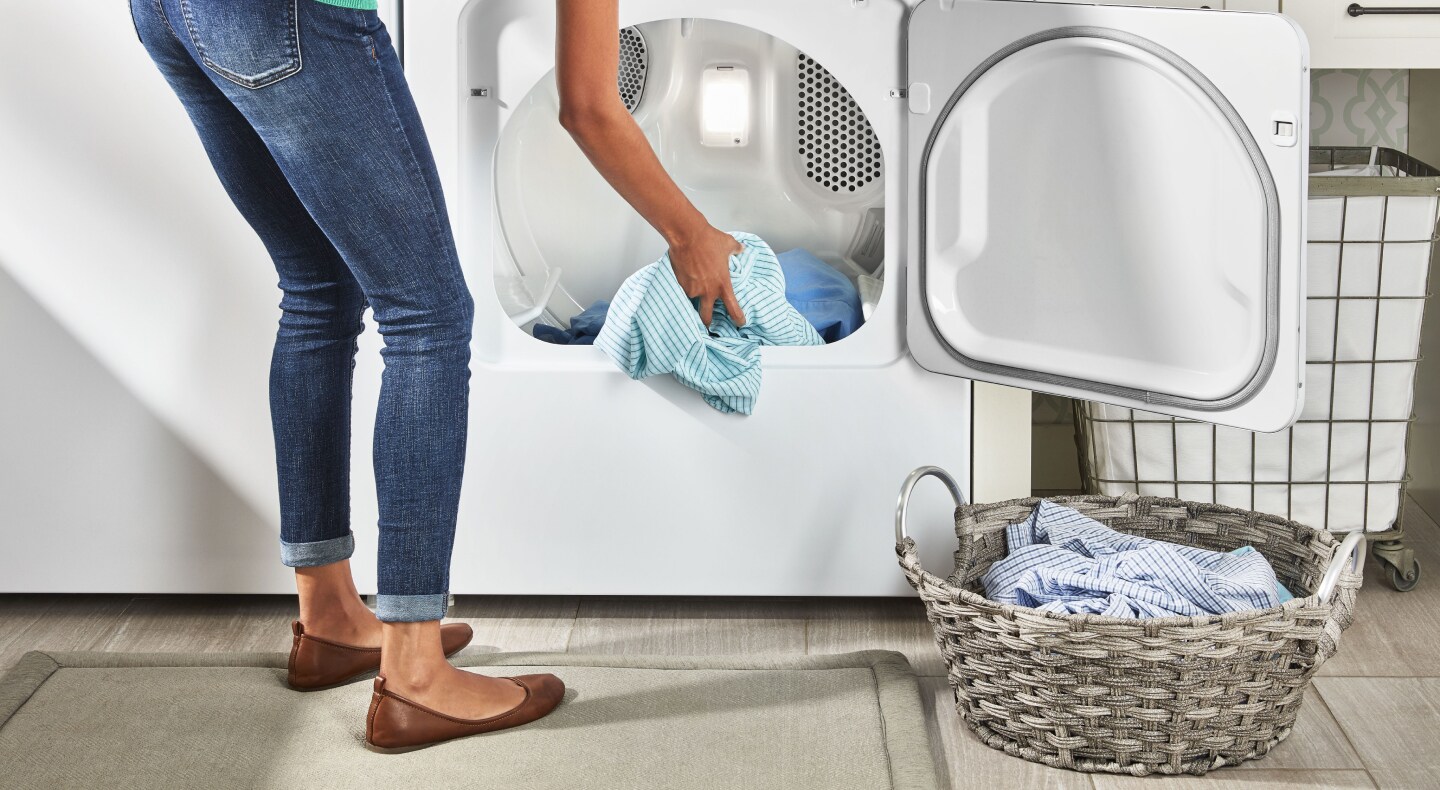 Person placing laundry in a laundry basket Person placing laundry in a laundry basket