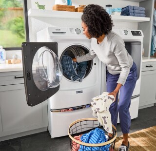 Person loading laundry into a front load washing machine