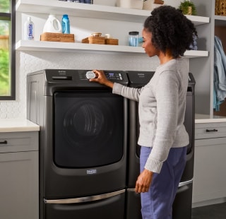 Person selecting a setting on a front load washing machine