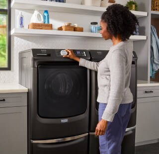 Person selecting a setting on a front load washing machine