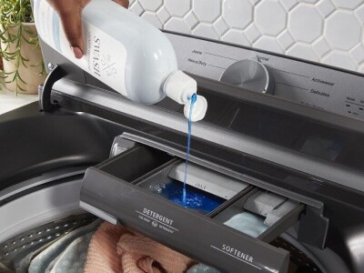 Hand pouring swash liquid detergent into washing machine