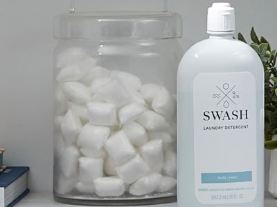 Bottle of liquid detergent next to jar of laundry pods