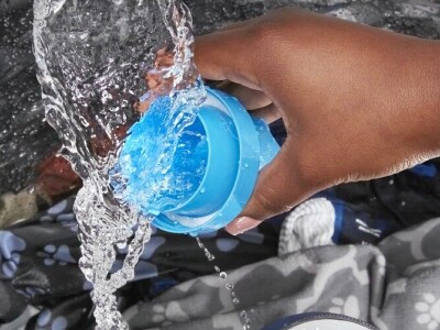 Hand pouring liquid detergent into washing machine