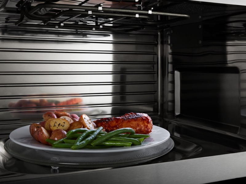 Chicken, potatoes and green beans on a plate inside a microwave Chicken, potatoes and green beans on a plate inside a microwave