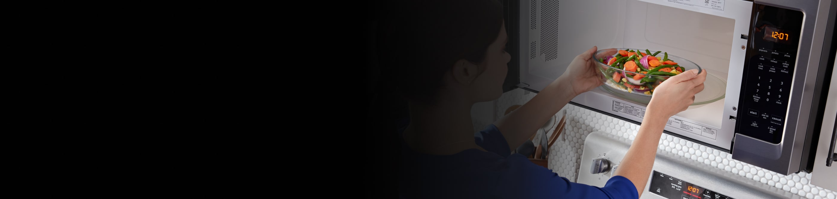 Person placing a bowl of vegetables inside a microwave