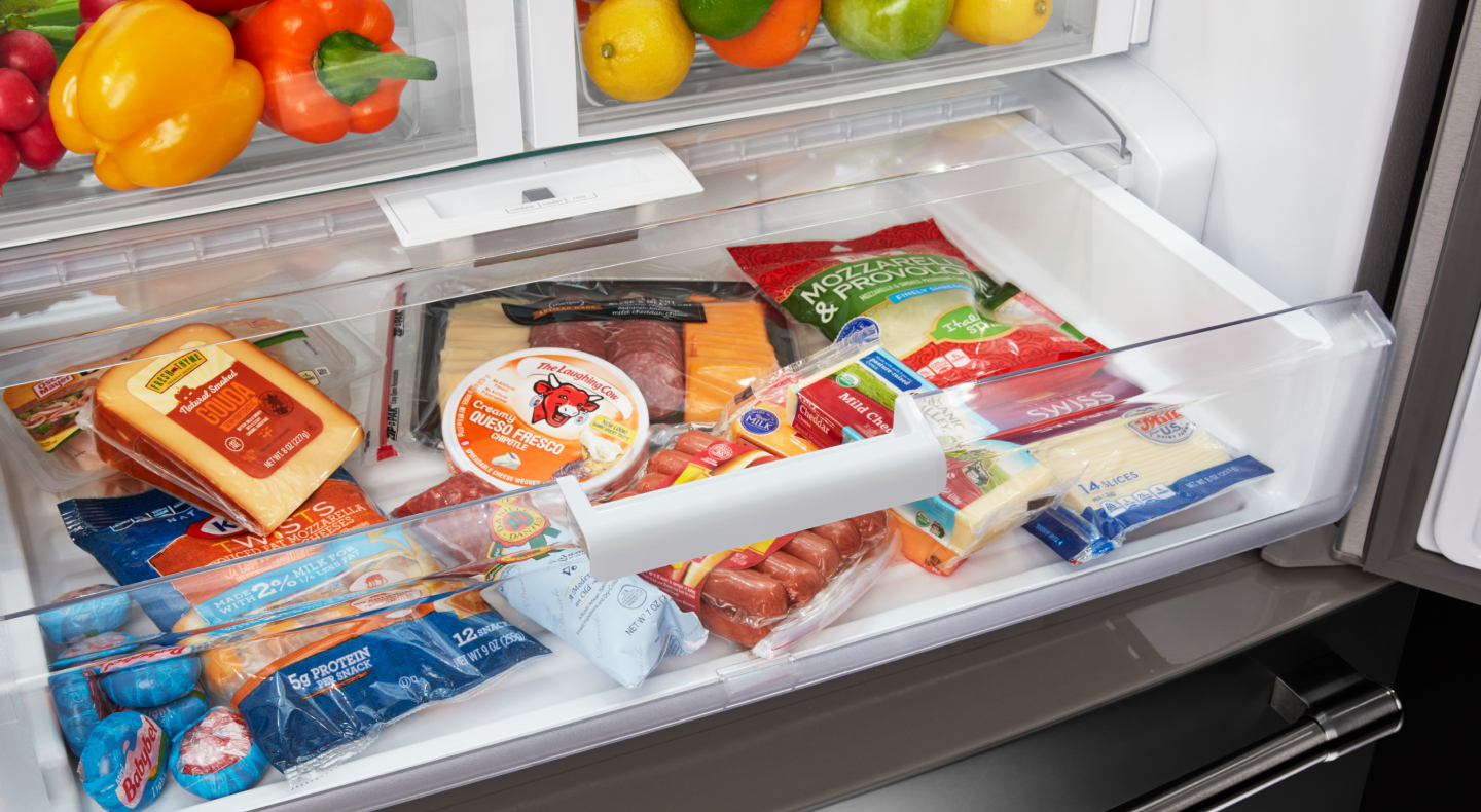 An open deli drawer of a Maytag® refrigerator with fresh food. An open deli drawer of a Maytag® refrigerator with fresh food.