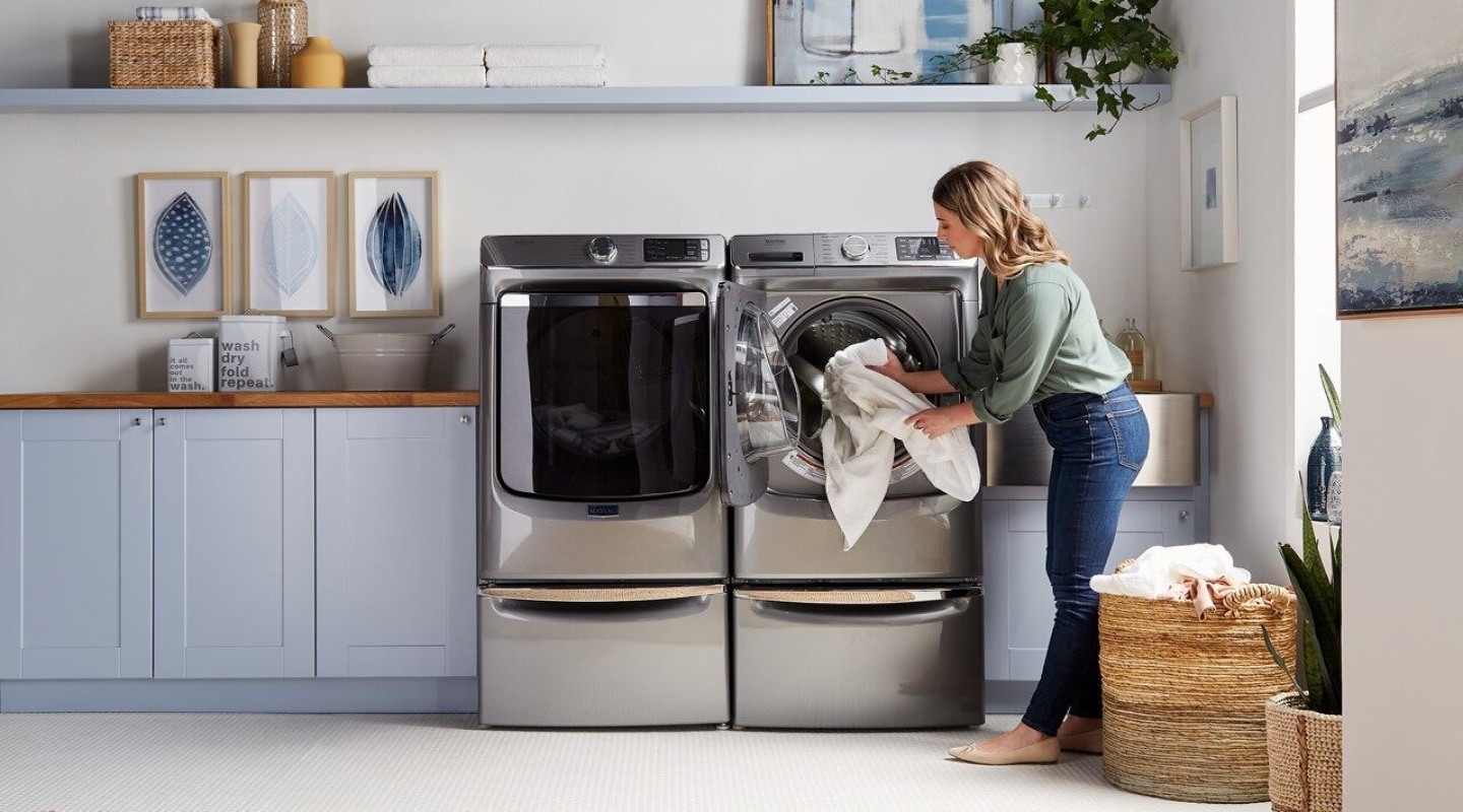 Woman loading a washer and dryer with laundry Woman loading a washer and dryer with laundry