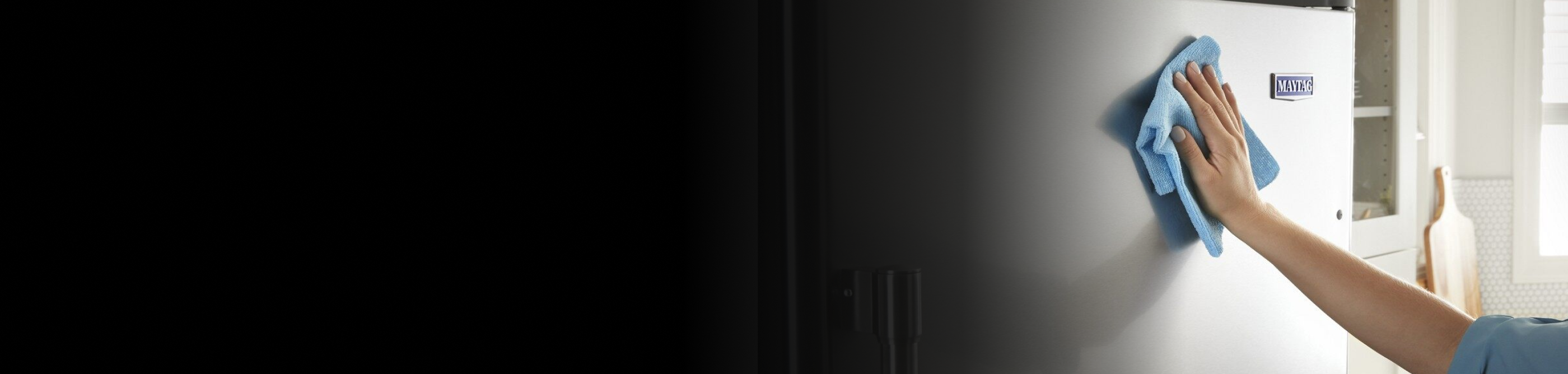 Person cleaning a stainless steel appliance