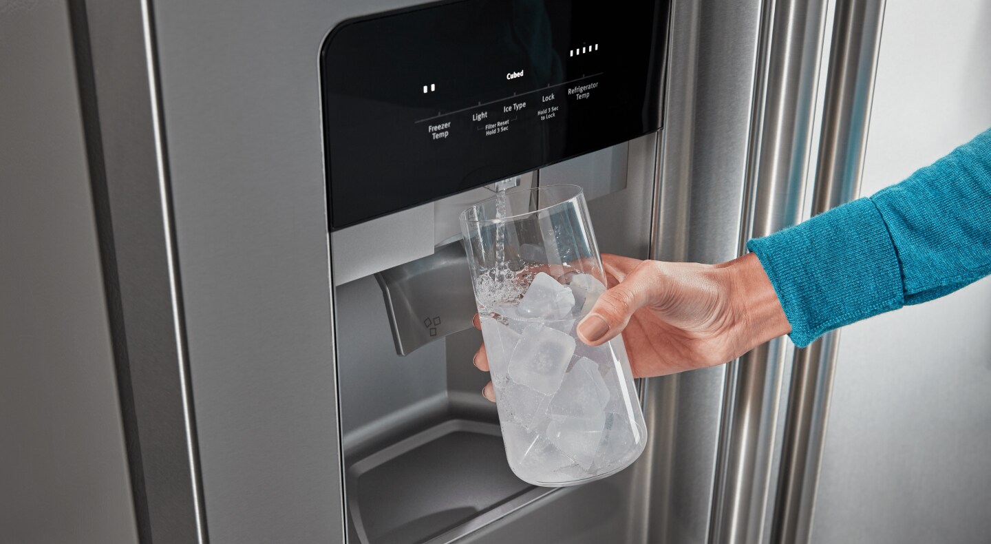 Person filling a glass with the refrigerator water dispenser