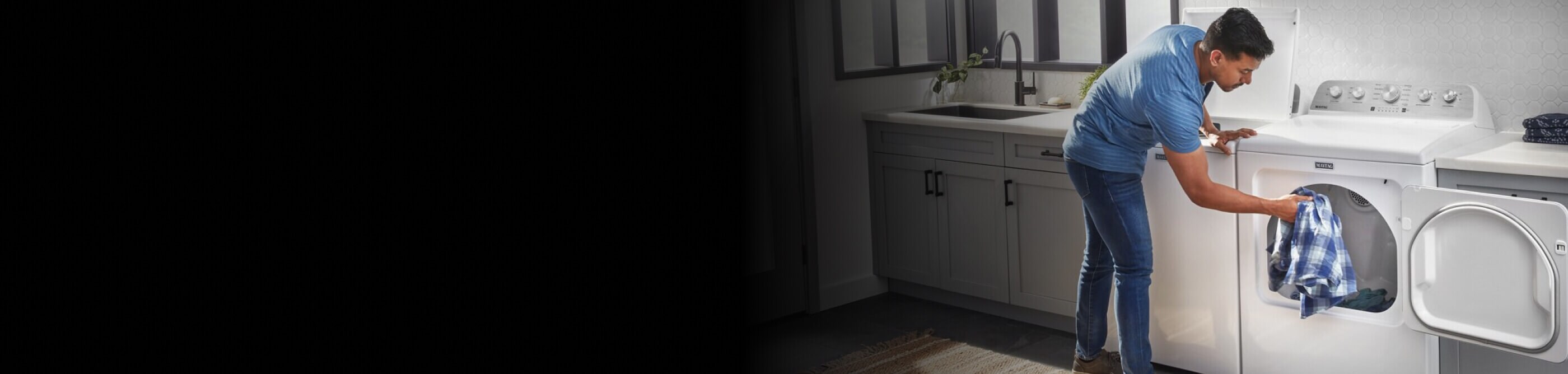 A man puts a shirt in a white Maytag® dryer