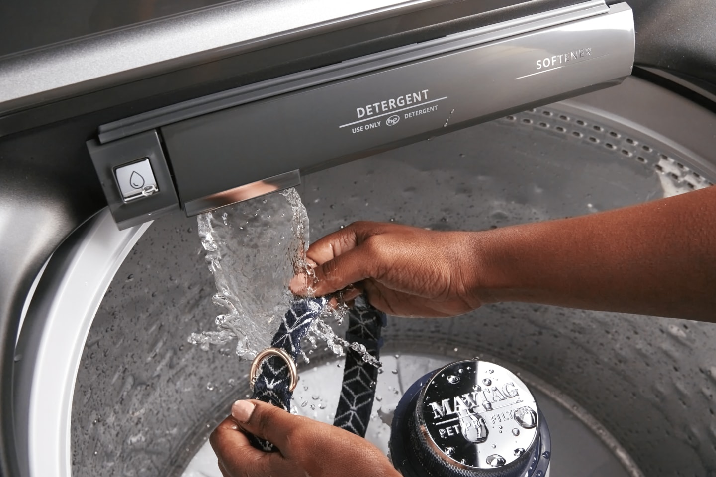 Person washing dog’s neck collar with Maytag® washer’s built-in faucet Person washing dog’s neck collar with Maytag® washer’s built-in faucet