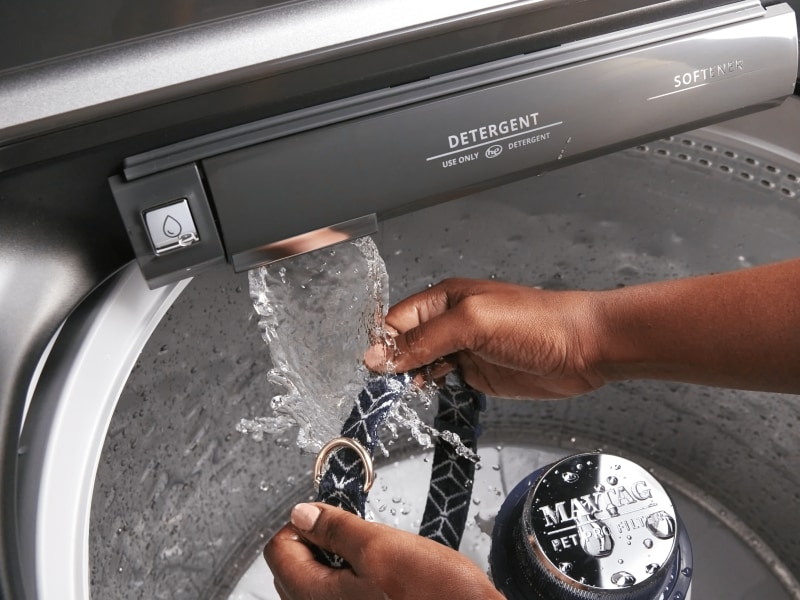 Person washing dog’s neck collar with Maytag® washer’s built-in faucet Person washing dog’s neck collar with Maytag® washer’s built-in faucet