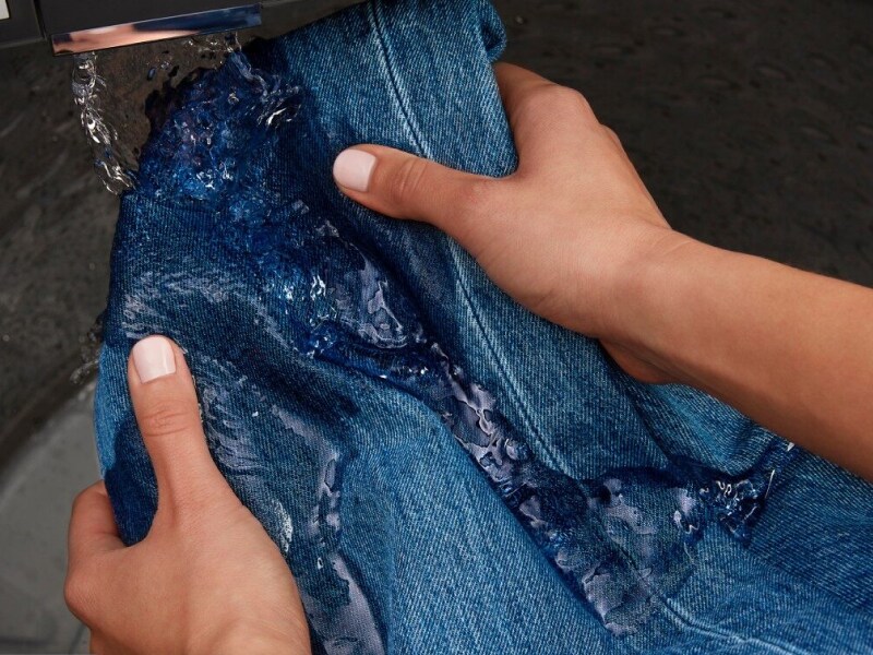 Hands rinsing denim under built-in faucet