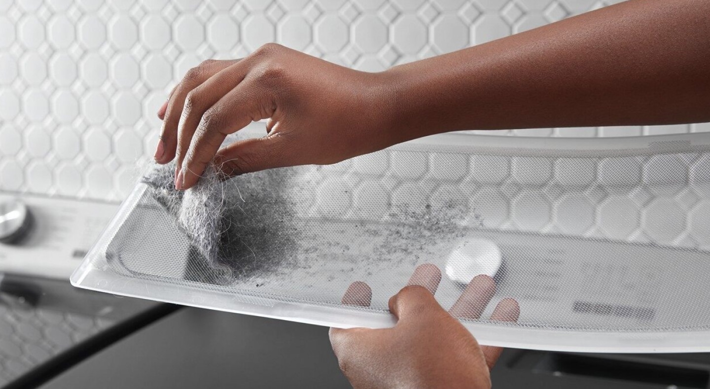 Person removing lint from a dryer lint trap  Person removing lint from a dryer lint trap