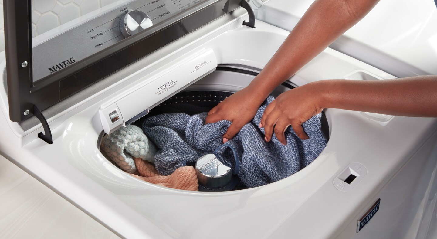 Person loading laundry into a washer