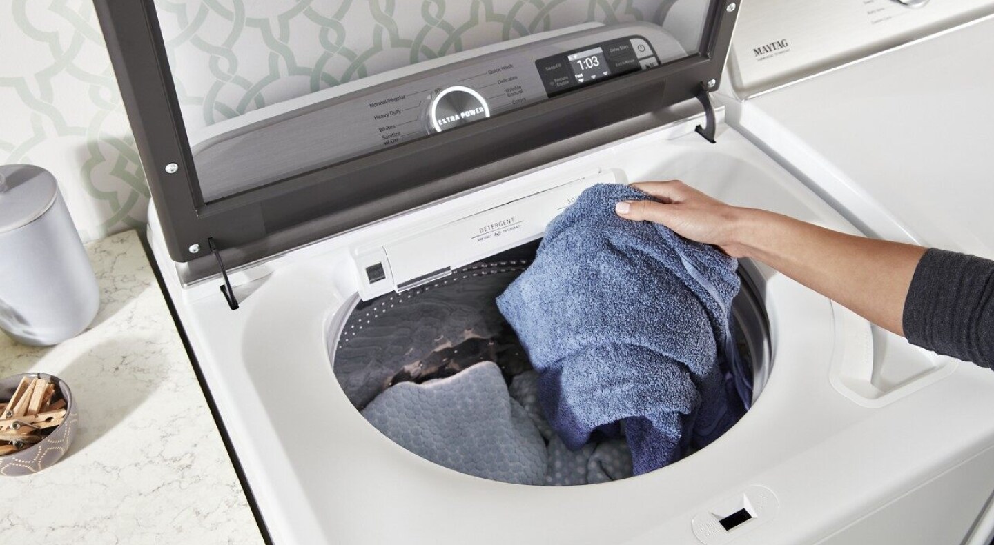 Person loading a towel into a washing machine