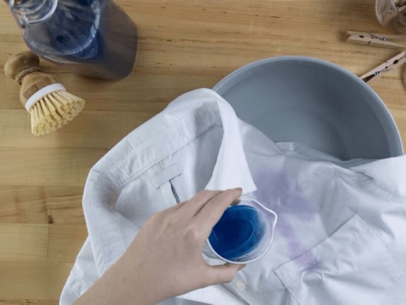 Person pouring detergent over white shirt Person pouring detergent over white shirt