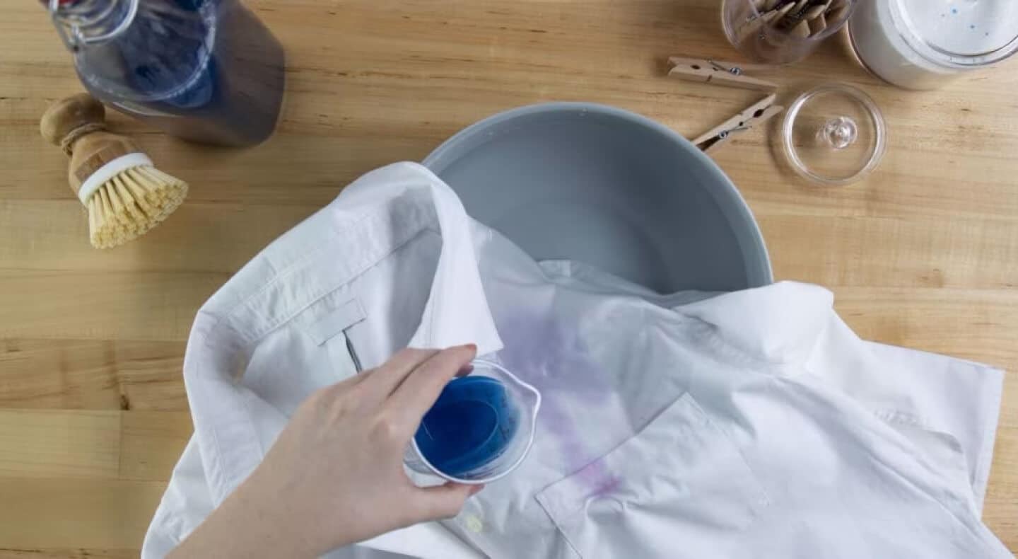 Person pouring detergent over white shirt Person pouring detergent over white shirt