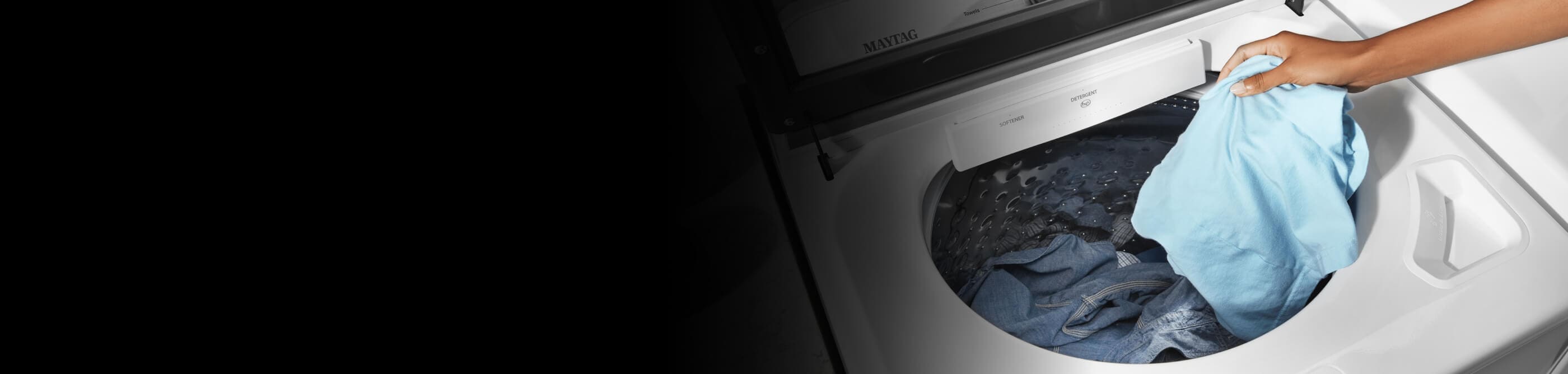 Person putting a blue shirt into a washing machine