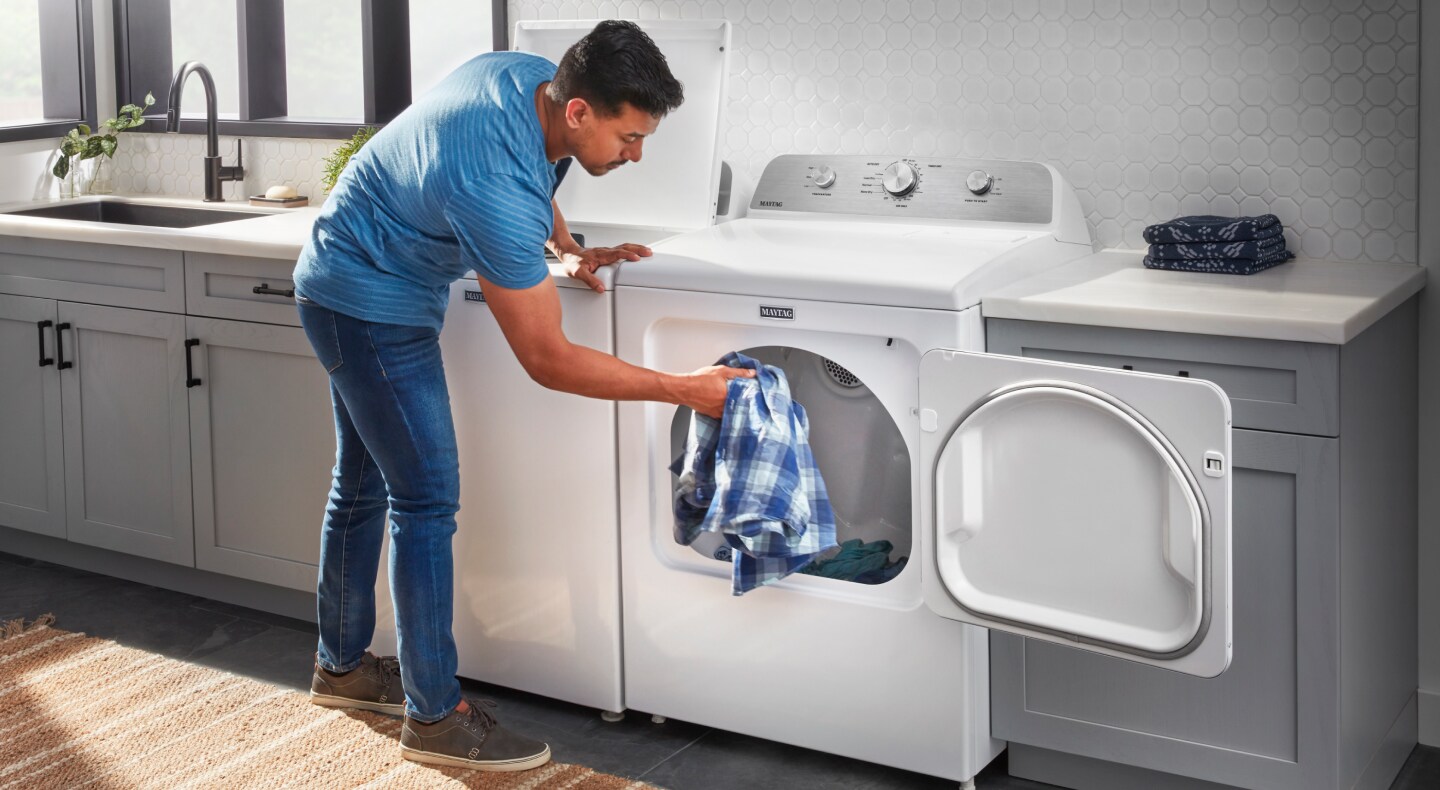 Person transferring a load of laundry from washer to dryer