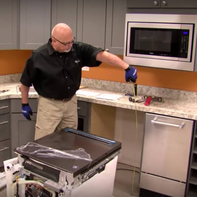 A person measuring space for installing a dishwasher